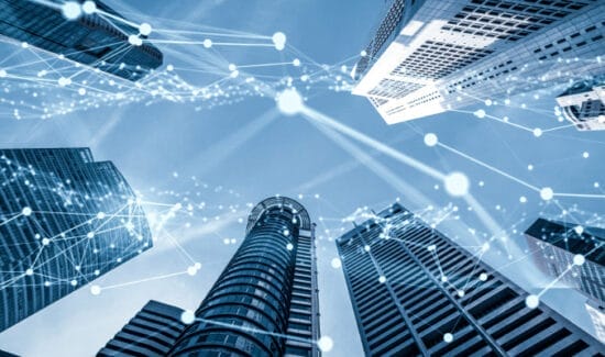 Looking up at tall skyscrapers against a blue sky, with glowing network lines and nodes overlaid, suggesting connectivity and technology integration in urban settings.