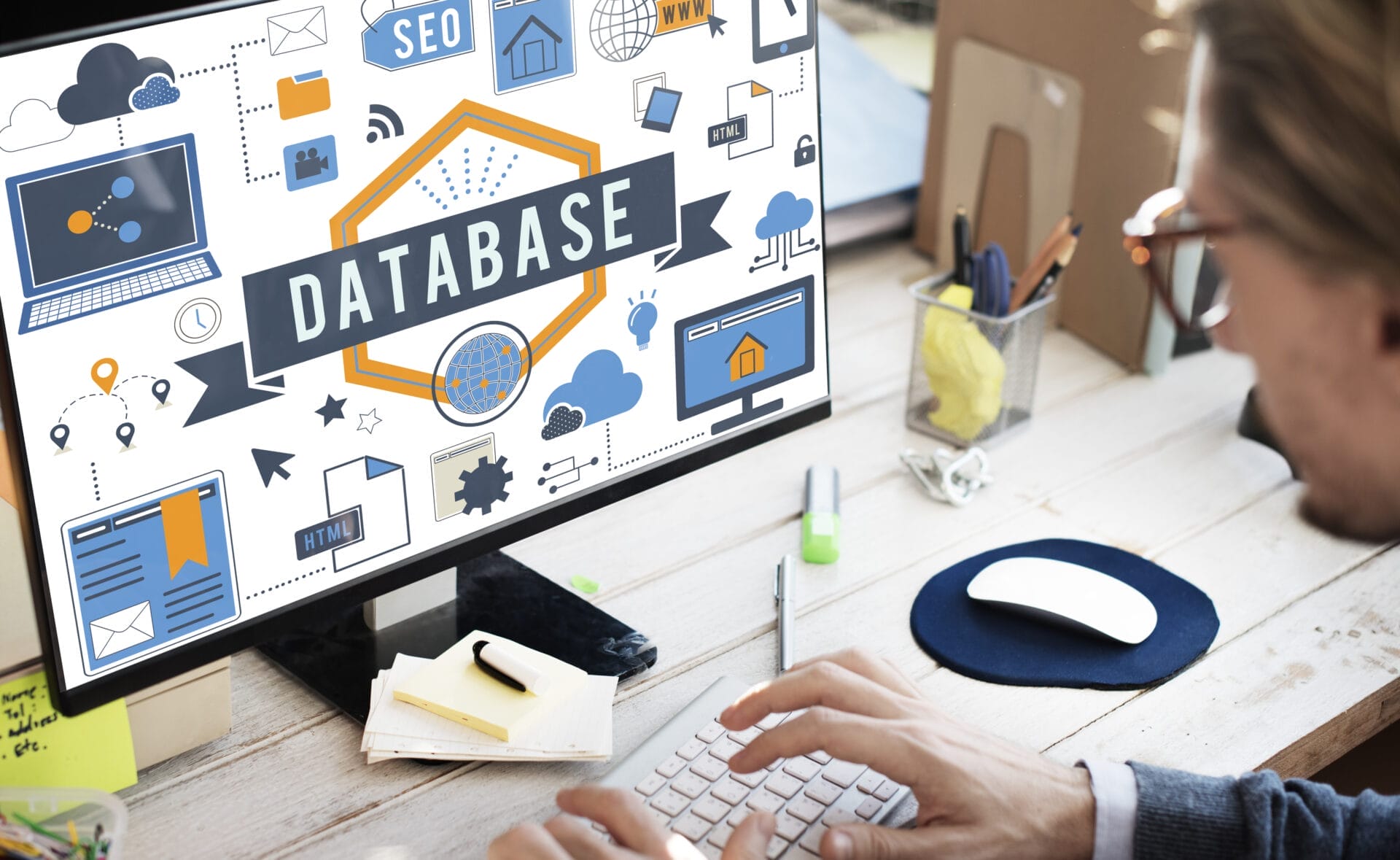 Person working on a computer displaying a graphic with the word "DATABASE" surrounded by icons related to technology and data, highlighting the importance of database performance management for seamless operations.