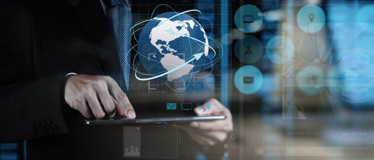 Person in a suit using a tablet with a digital globe and technology icons overlay.